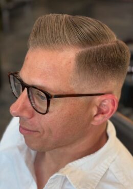 Classic comb-over fade haircut with sharp part by Kenzy at Take Pride Barbershop in Portland.